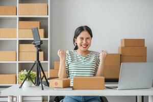 Starting Small business entrepreneur SME freelance, Portrait young woman working at home office, BOX, smartphone, laptop, online, marketing, packaging, delivery, b2b, SME, e-commerce concept. photo