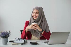 Portrait of beautiful muslim businesswoman smiling at the camera, sitting at her desk. photo