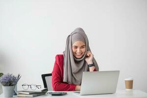 retrato de hermosa musulmán mujer de negocios sonriente a el cámara, sentado a su escritorio. foto