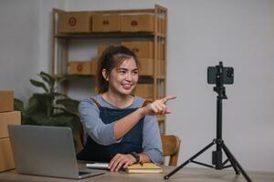 Asian blogger review products and video camera on her phone, sell them online, and showcase her products online on social media. ecommerce business live streaming vlog new normal concept photo