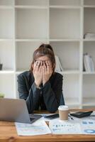 Confused Asian woman thinking hard about how to solve problems online looking at laptop screen. Serious Asian businesswoman worried focused on solving difficult computer at office photo