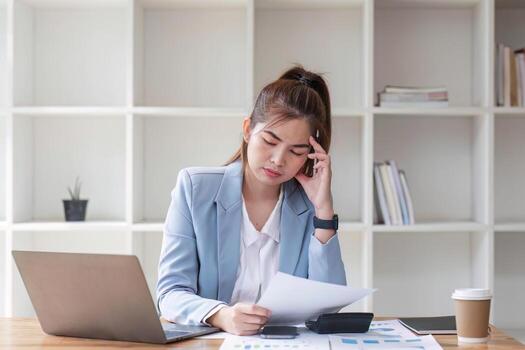 confuso asiático mujer pensando difícil acerca de cómo a resolver problemas en línea mirando a ordenador portátil pantalla. grave asiático mujer de negocios preocupado enfocado en resolviendo difícil computadora a oficina foto