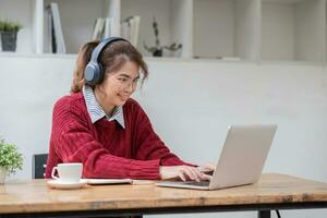 asiático hembra estudiante estudiar en línea en clase, estudiar en línea, vistiendo auriculares, acecho vídeo llamar, zoom, contento asiático hembra aprendizaje idioma en línea con computadora ordenador portátil. foto