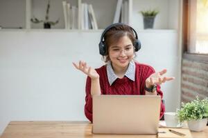 asiático hembra estudiante estudiar en línea en clase, estudiar en línea, vistiendo auriculares, acecho vídeo llamar, zoom, contento asiático hembra aprendizaje idioma en línea con computadora ordenador portátil. foto