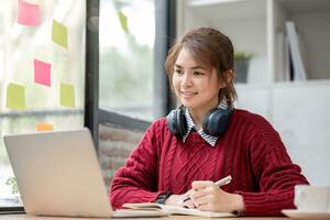 asiático hembra estudiante estudiar en línea en clase, estudiar en línea, vistiendo auriculares, acecho vídeo llamar, zoom, contento asiático hembra aprendizaje idioma en línea con computadora ordenador portátil. foto