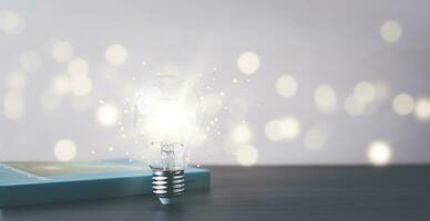 Thinking and creative concept, Light bulb on the Book and light bulb style bokeh vintage dark background,Concept The idea of reading books, knowledge, and searching for new ideas. photo