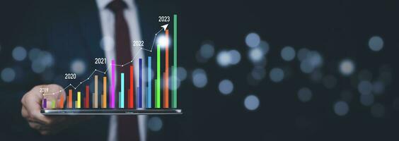 Businessman touch growth data chart arrow with diagram 2023 budget, Businessman pointing arrow graph corporate future growth year 2022 to 2023, Development to success and motivation. photo