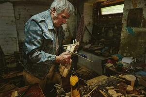 Mature carpenter in action in his workshop. Craftspeople, artist in action, talent, skill and hobby concepts photo