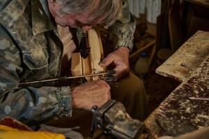 A carpenter making a handmade wooden model of a sailboat in a home workshop photo