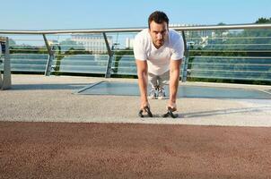 muscular hermoso atractivo medio Envejecido caucásico hombre, determinado atleta haciendo empujar UPS desde el piso durante un intenso al aire libre rutina de ejercicio en un urbano vaso puente en un calentar temprano verano día foto