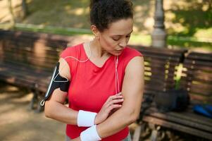 Beautiful Hispanic woman with healthy clean fresh skin and aesthetic fit muscular body in sportswear standing on the city park while working out photo