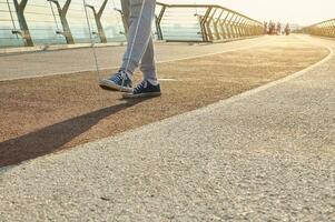 Close-up of the legs of a male athlete exercising outdoors with a skipping rope. Sportsman during morning cardio workout with jumping rope on city bridge at dawn. Motion, active and healthy lifestyle photo