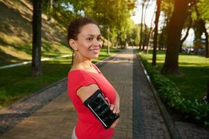 retrato de un confidente 40 años antiguo africano americano mujer en ropa de deporte en pie en bosque ciudad parque con su brazos cruzado y sonriente con un hermosa con dientes sonrisa durante su Mañana correr o rutina de ejercicio foto