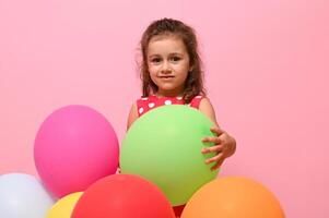 adorable hermosa niño, bebé chica, 4 4 años niño abrazando vistoso globos, aislado terminado rosado antecedentes con Copiar espacio. cumpleaños evento concepto, contento mujer día, niños proteccion día. foto