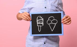 Cropped view of a boy hands holding a chalkboard with drawn ice cream against pink background with copy space photo