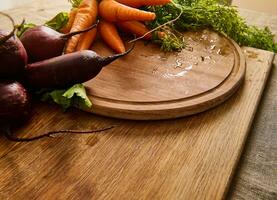 estacional crudo vegetales. racimos de Fresco orgánico remolacha y bebé zanahorias con tapas en un de madera corte tablero. vegano comida antecedentes foto