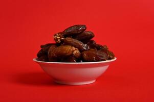 A plate with delicious fresh dates to break the fast in Ramadan. Red background, copy space. photo