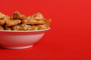 Isolated studio shot on red background of cropped plate with delicious Arabian Moroccan dessert for religious events on a plate photo