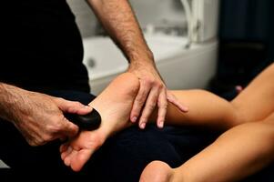 Feet massage with volcanic hot stone in Ayurvedic wellness spa center. Total body restoration concept photo