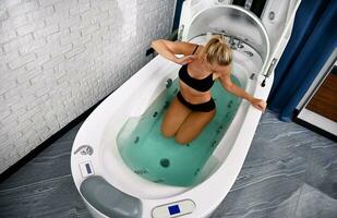 Top view of a woman with perfect body receiving beauty treatment in bathtub of opened spa capsule photo