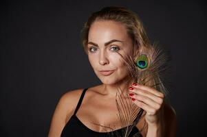 Beautiful woman in black underwear holding a peacoch feather photo