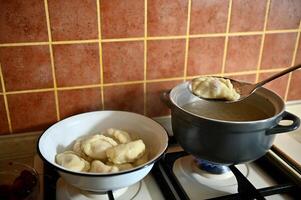 The pastry chef takes out cooked dumplings from boiling water into a colander. Process of cooking dumplings step by step. Close-up, food background. photo