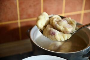 Close-up of a pastry chef taking out cooked dumplings from boiling water into a colander. Process of cooking dumplings step by step. Close-up, food background. photo