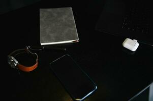 Top view of office accessories, laptop, earphones on the box, watch, mobile phone and gray notepad on wooden desk photo