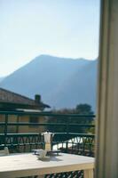 Italian coffee maker and a cup of espresso on the table, on balcony overlooking a mesmerizing landscape of Italian Alps photo