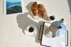 parte superior vista. desayuno en italiano estilo. dos tazas de Café exprés café, recién horneado croissants y percolador en el mesa foto