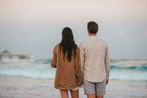 Young couple on the beach vacation walking at sunset photo