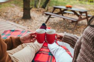 Hot cups of tea in hands in woollen sweater on background of cozy house photo