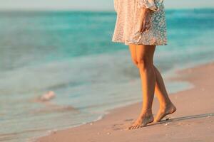 Female legs on the beach closeup. Woman in dress walking on the beach photo