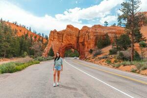 Young happy woman in background of natural stone arch Bridge in the Red Canyon National Park in Utah, USA photo