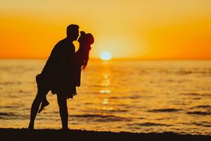 joven Pareja en blanco playa durante verano vacaciones a puesta de sol foto