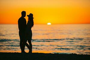 Happy couple on the beach at beautiful sunset on background photo