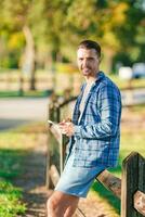 Portrait of young man with smart phone in the park looking at camera photo