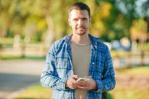 Young man using mobile phone outdoor in the park photo