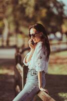 Young woman talking on the mobile phone outdoor in the park photo