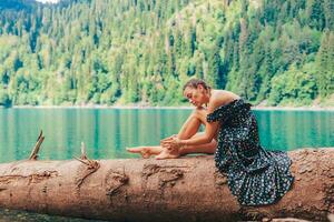 Happy romantic woman sitting by lake splashing water at perfect blue Lake Ritsa. Abkhazia photo