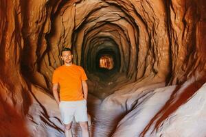 joven caminante hombre en popular sendero barriga de el continuar túnel cueva en kanab foto