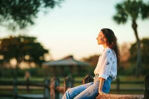 Portrait of happy young woman outdoor in the park at sunset photo