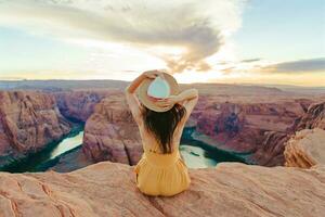 Beautiful woman in yellow dress on the edge of the cliff at Horseshoe Band Canyon in Paje, Arizona. Beautiful nature in USA photo