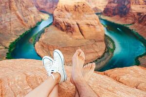 contento Pareja en el borde de el acantilado a herradura banda cañón en página, Arizona. aventuras y turismo concepto. hermosa naturaleza en Estados Unidos foto