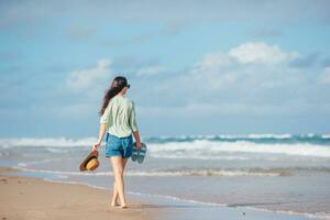 a woman in a hat and shorts standing on the beach photo