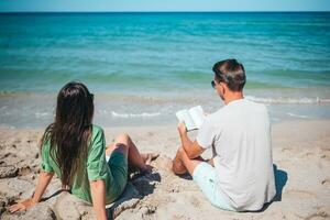 Young couple reading books on tropical beach photo