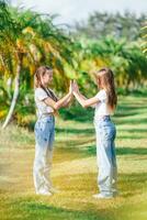 dos muchachas en pantalones en un campo con palma arboles foto