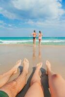 Closeup of the feet of family on the white sandy beach. Children play on the beach in shallow water on summer vacation photo