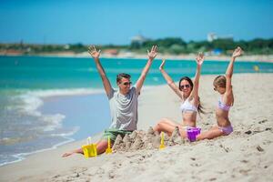 familia disfrutando hora en el playa haciendo arena castillo juntos en el costa foto