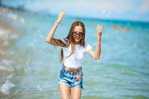 Little happy girl splashing in clear turquoise water photo